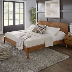 a bedroom with gray walls and wooden bed frame, white pillows and throw rugs