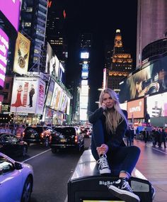 a woman sitting on top of a bench in the middle of a city