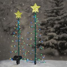 a small christmas tree in the snow with two star decorations on it's top