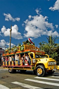 a yellow truck with people in it driving down the street