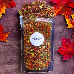 a bag filled with lots of colorful candies on top of a wooden table next to autumn leaves