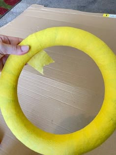 someone is making a paper mache wreath out of cardboard and yellow construction material with scissors