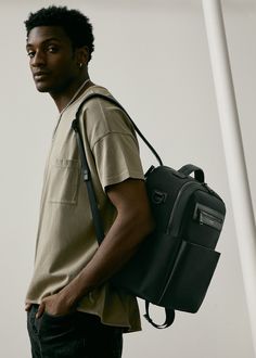 a young man carrying a black bag on his back and looking off to the side