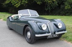 an old fashioned sports car is parked on the side of the road