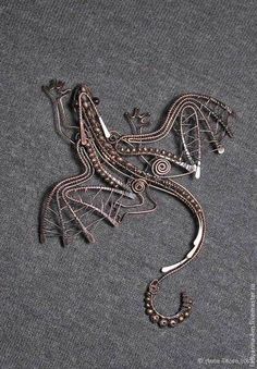 an intricately designed metal dragon on a gray surface with beads and chains attached to it