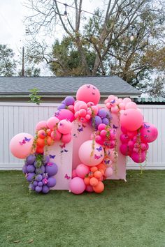 the balloon arch is decorated with pink, purple and orange balloons