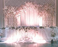 an image of a wedding setup with flowers on the wall and lights in the background