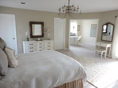 a bedroom with a bed, dressers and mirror in it's center area