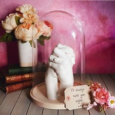 there is a glass dome with flowers in it next to books and a sign that says i'll always hold you tight