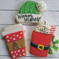 three decorated cookies sitting next to each other on a white wooden surface with the words warm wishes written above them