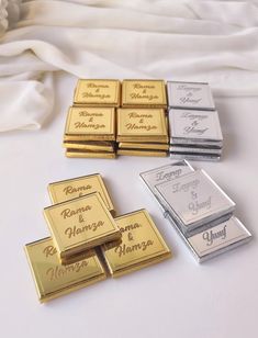 four different types of gold and silver bar magnets on a white table with flowers in the background