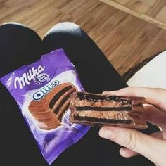 a person holding a piece of chocolate cake in their left hand and a bag of milk on the other