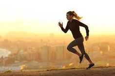 a woman running on top of a hill with the city skyline in the back ground