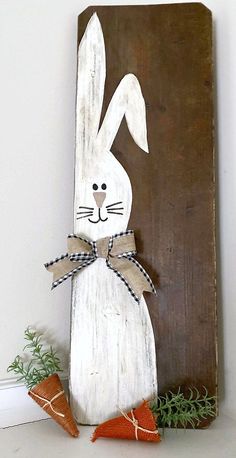 a wooden sign with a bunny painted on it and two carrots next to it