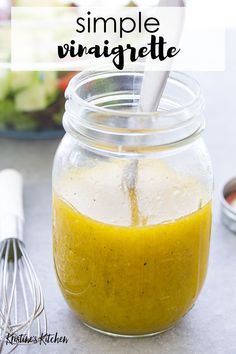 a glass jar filled with yellow liquid next to a whisk and other ingredients