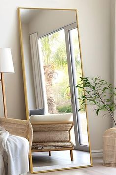 a large mirror sitting on top of a wooden floor next to a chair and table