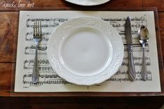 a place setting with music sheet napkins and silverware on the place mat in front of it