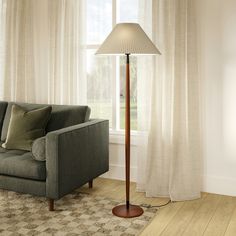 a living room scene with focus on the floor lamp and couch in front of the window