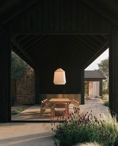 an outdoor dining area with wooden tables and chairs, surrounded by tall grass in the foreground