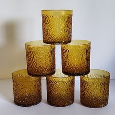 four yellow glass cups are stacked on top of each other