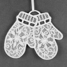 an ornament hanging from a string on a gray background, with white lace