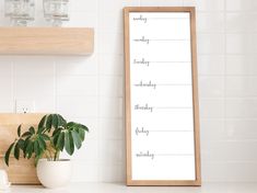 a wooden framed sign sitting on top of a counter next to a potted plant