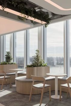 an office with large windows and plants in the middle of it's desks