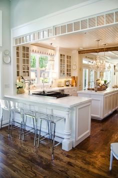 a large kitchen with white cabinets and an island in the middle of the room that has bar stools on it