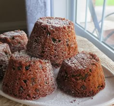 several cakes on a white plate next to a window