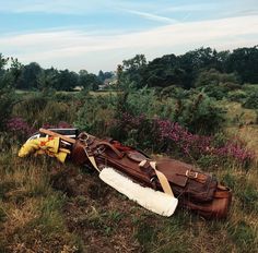 an old suitcase laying on its side in the middle of a field with purple flowers