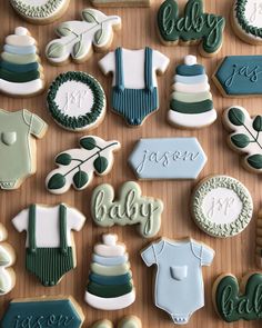 baby shower cookies are arranged on a wooden table with green and white decorations, including ones that say it's a boy