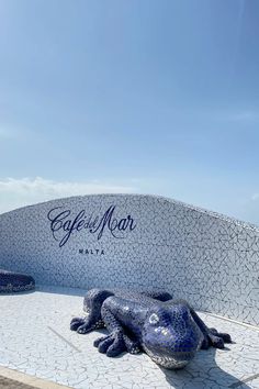 a blue frog statue sitting in front of the entrance to cafe de mar