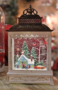 a christmas scene is displayed in a glass box on a wooden table next to a red truck