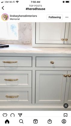 an image of a white kitchen with gold handles on the drawers and marble countertops