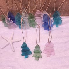 small glass christmas trees and starfish hanging from twine strings on a white blanket