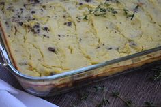 a casserole dish with meat and vegetables in it sitting on a table next to napkins