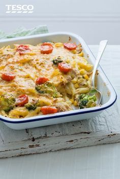 a casserole dish with broccoli, tomatoes and cheese in it on a table