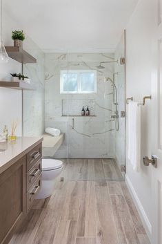 a bathroom with wood flooring and white walls, along with a walk in shower