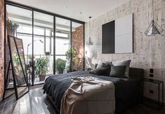 a bedroom with brick walls and flooring has a large bed in the middle, along with plants on the wall