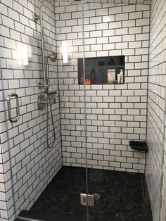 a walk in shower with black and white tile on the walls, floor and wall