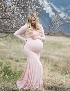 Spring maternity photo shoot fun! This long-sleeve scoop-neck fitted maternity gown with a flare bottom is a modest maternity gown that exudes classic beauty.  #maternitygown #prettyinpink #spring #momtobe Modest Fitted Maternity Dress, Modest Fitted Maternity Maxi Dress, Pink Long Sleeve Maternity Maxi Dress, Long Sleeve Pink Maxi Dress For Maternity, Fitted Maternity Gown For Spring, Spring Fitted Maternity Gown, Long Sleeve Maternity Dress For Wedding, Stretch Maternity Dresses With Long Sleeves, Elegant Long Sleeve Maternity Dress, Bump Friendly