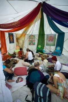 a group of people sitting on top of a bed in a tent