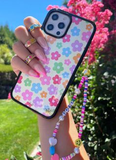 a woman's hand holding an iphone case with flowers and beads on the back