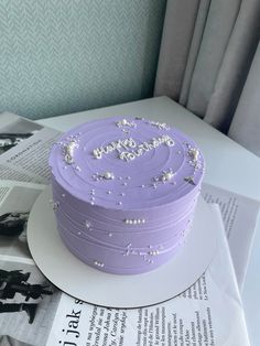 a purple cake sitting on top of a white plate next to a book and magazine