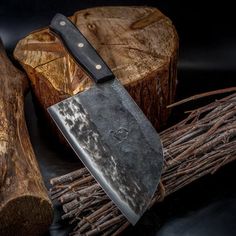 a knife sitting on top of a piece of wood next to some sticks and logs