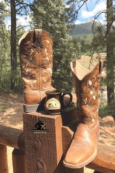 a pair of cowboy boots sitting on top of a wooden bench next to a phone