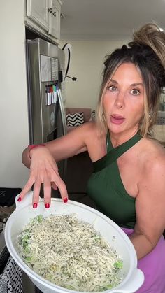 a woman is holding a large bowl of food