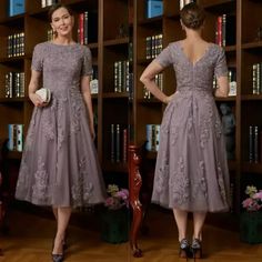 a woman standing in front of a bookshelf wearing a dress