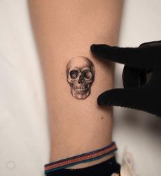 a woman's arm with a small skull tattoo on the left side of her leg