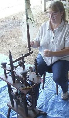 a woman sitting on top of a chair next to an old fashioned machine with wheels